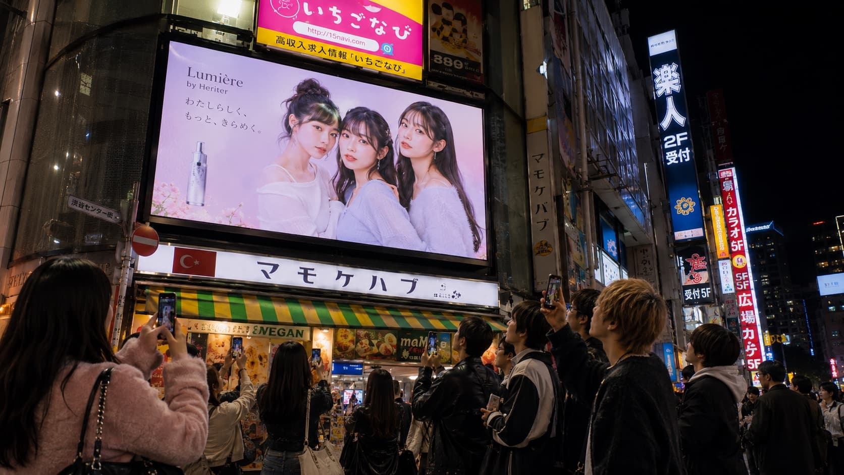 渋谷センター街のミチビキ サイネージに通行人がスマートフォンを向けている様子